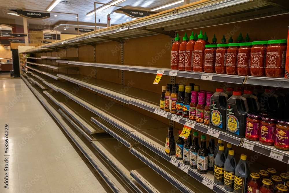 Empty grocery store shelves with many products missing. Stock Photo