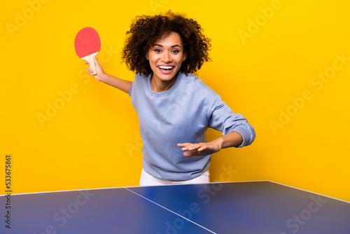 Portrait of positive cheerful person hold ping pong racket playing tennis isolated on yellow color background