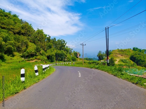 a highway under the hills against the background of a bright blue sky