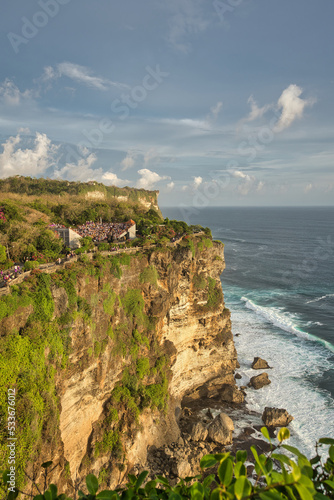 Beautiful sky with clouds over waves in the sea hitting crushing against cliffs photo