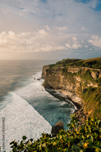 Beautiful sky with clouds over waves in the sea hitting crushing against cliffs