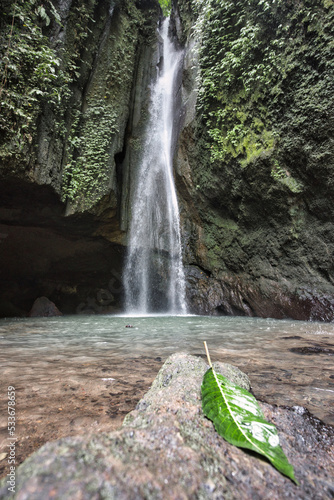 Waterfall in the forest and with leaf on a stone in the foreground - Bali
