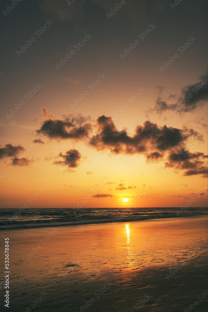 Beautiful sunset sunrise at the beach with dramatic clouds in the blue purple yellow sky over the sea - Bali