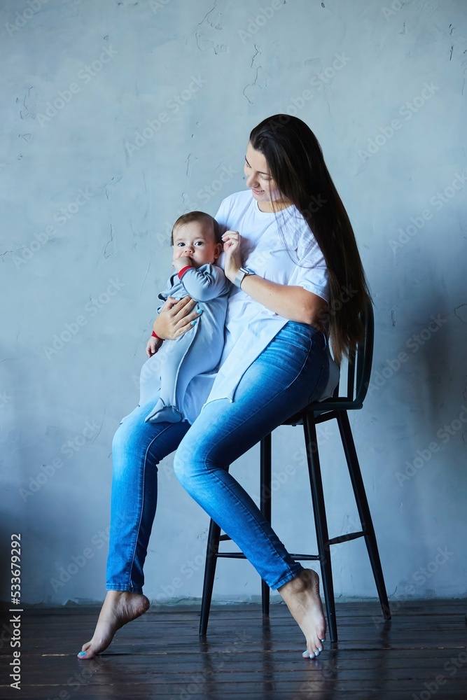 Mom with her newborn baby boy in a modern style room. The concept of motherhood and childhood.