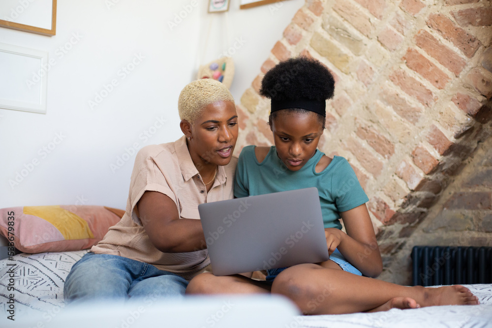 African American mother helping daughter with homework using a laptop African American mother helping daughter with homework using a laptop