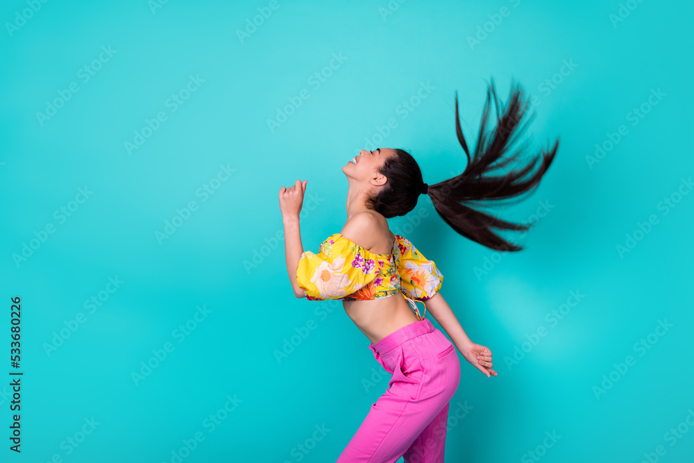 Photo of pretty adorable lady wear yellow blouse dancing air blowing hairdo flying empty space isolated turquoise color background