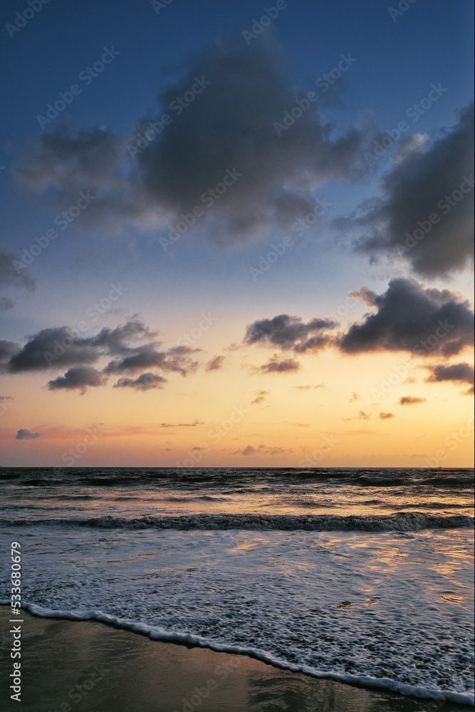 Beautiful sunset sunrise at the beach with dramatic clouds in the blue purple yellow sky over the sea - Bali