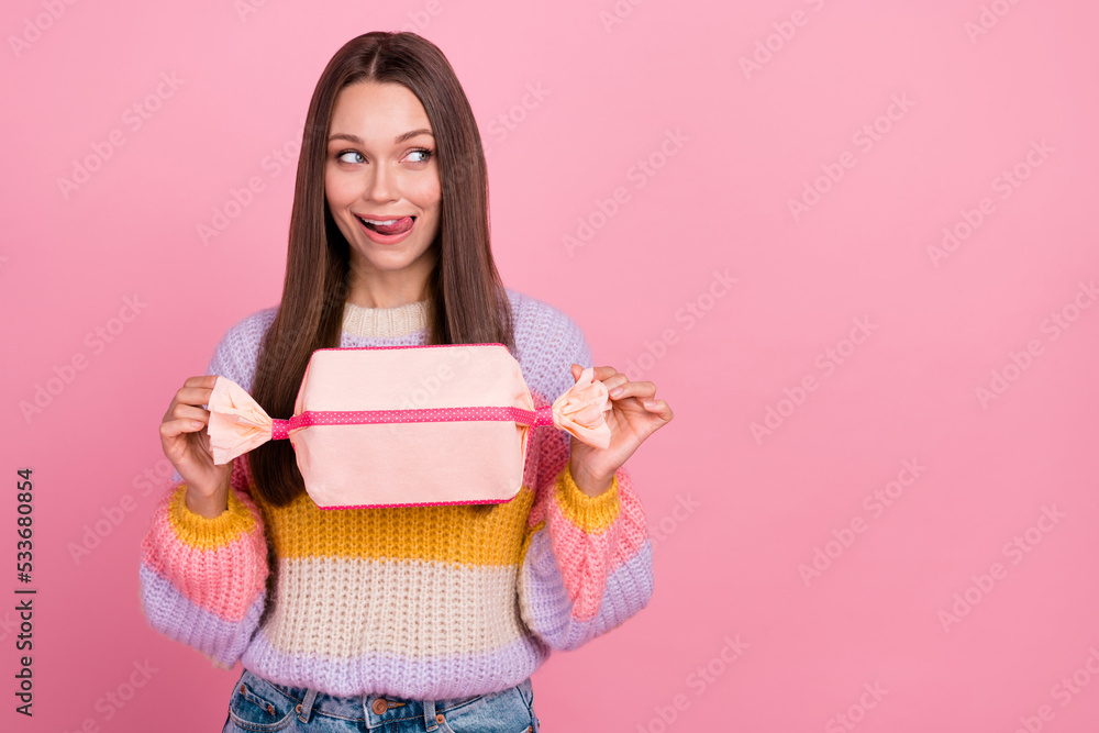 Portrait of cheerful pretty lady arms hold large candy giftbox tongue lick teeth look empty space isolated on pink color background Portrait of cheerful pretty lady arms hold large candy giftbox tongue lick teeth look empty space isolated on pink color background