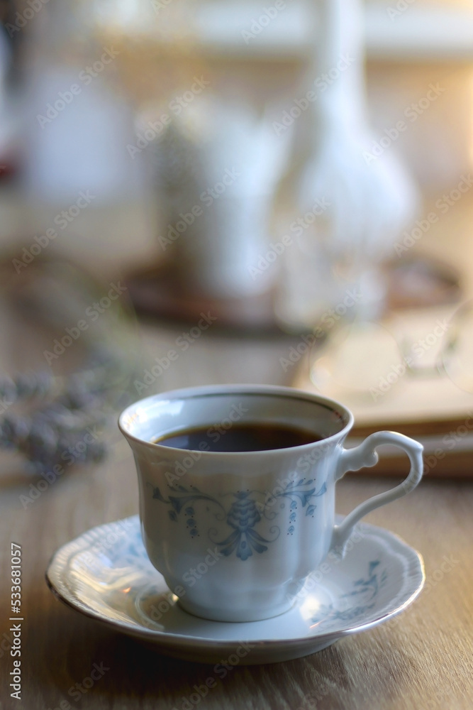 Cup of tea, plate with chocolate chip cookies, open book, reading glasses, lit candles and dry lavender flowers. Hygge at home, selective focus. Cup of tea, plate with chocolate chip cookies, open book, reading glasses, lit candles and dry lavender flowers. Hygge at home, selective focus.