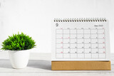 September 2023 Desktop calendar for planners and reminders on wooden table with plant pots on a white background.