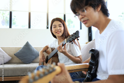 A woman and a man play guitar together as a guitar jam with an acoustic guitar and an electric guitar in the same song.