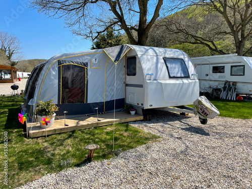 An open tent in front of a travel trailer at a caravan campsite.