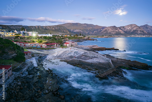 Evening view of Hermanus coastline, the Old Harbour in the foreground, the full moon rising above the Kleinrivier Mountains. Whale Coast, Overberg, Western Cape, South Africa. photo