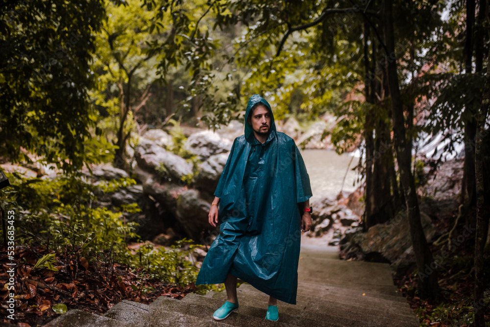 Man with a raincoat walking through a forest Man with a raincoat walking through a forest