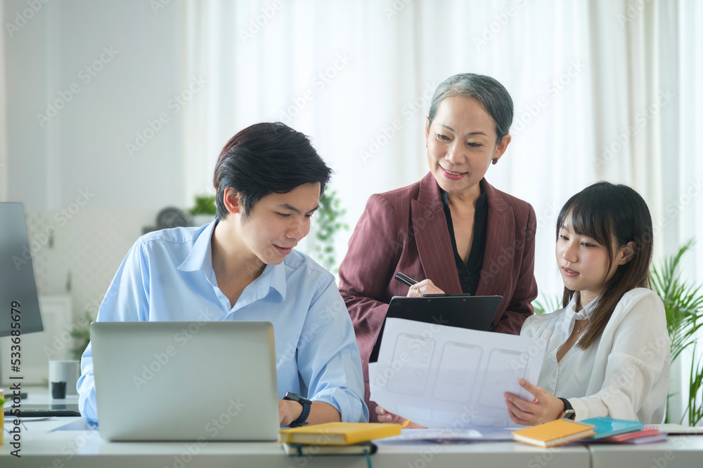 Smiling senior business woman discuss financial statistics, reviewing reports with young businesspeople in office. Smiling senior business woman discuss financial statistics, reviewing reports with young businesspeople in office.