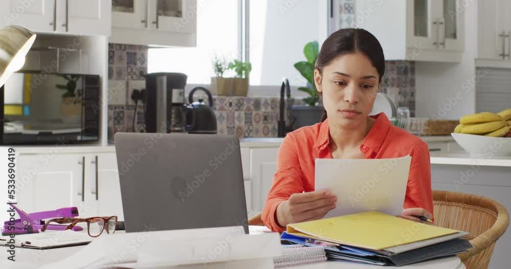 Biracial woman using laptop and working in kitchen Biracial woman using laptop and working in kitchen
