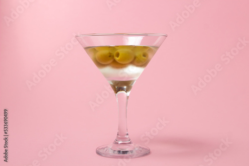Martini glass with olives on a pink background. Delicious alcoholic drink.