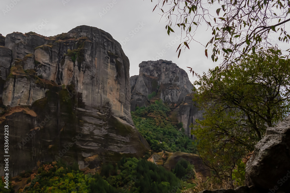 Panoramic view of unique rock formations near Holy Monastery of Varlaam on cloudy foggy day in Kalambaka, Meteora, Thessaly, Greece, Europe. Rocks overgrown with green moss creating moody atmosphere