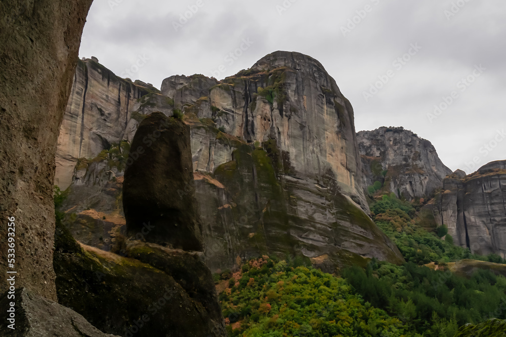 Panoramic view of unique rock formations near rock Aghio Pnevma (Holy Spirit) on cloudy foggy day in Kalambaka, Meteora, Thessaly, Greece, Europe. Rocks overgrown with moss creating moody atmosphere
