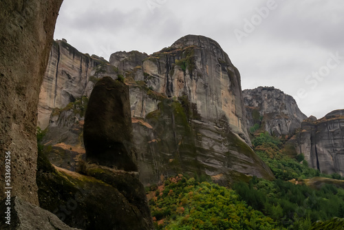 Panoramic view of unique rock formations near rock Aghio Pnevma (Holy Spirit) on cloudy foggy day in Kalambaka, Meteora, Thessaly, Greece, Europe. Rocks overgrown with moss creating moody atmosphere