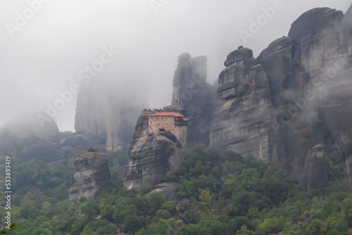 Scenic view of Holy Monastery of St Nicholas Anapafsas surrounded by misty fog on cloudy day  Kalambaka  Meteora  Thessaly  Greece  Europe. Dramatic landscape. Landmark build on unique rock formations