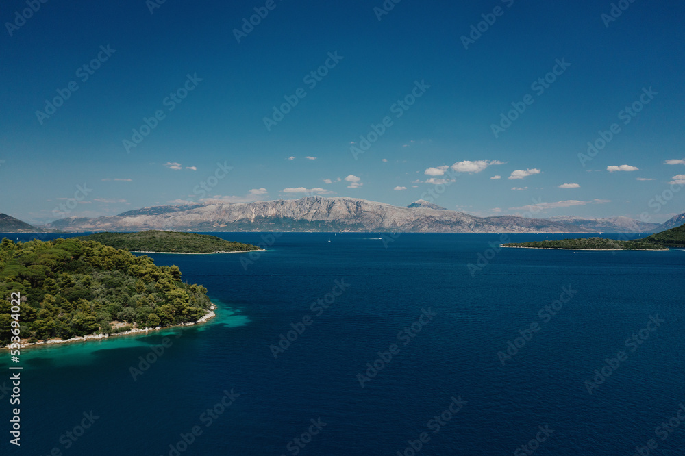 Seascape and sandy beach with turquoise clear waters and trees in Greece