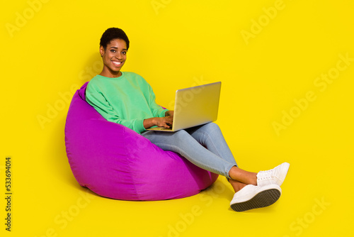 Full length body size view of attractive cheerful girl sitting in bag chair isolated over vivid yellow color background