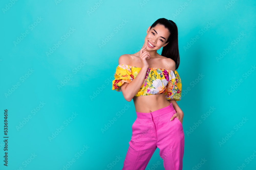 Photo of cute young lady stand near promo wear floral top pink pants isolated on teal color background Photo of cute young lady stand near promo wear floral top pink pants isolated on teal color background