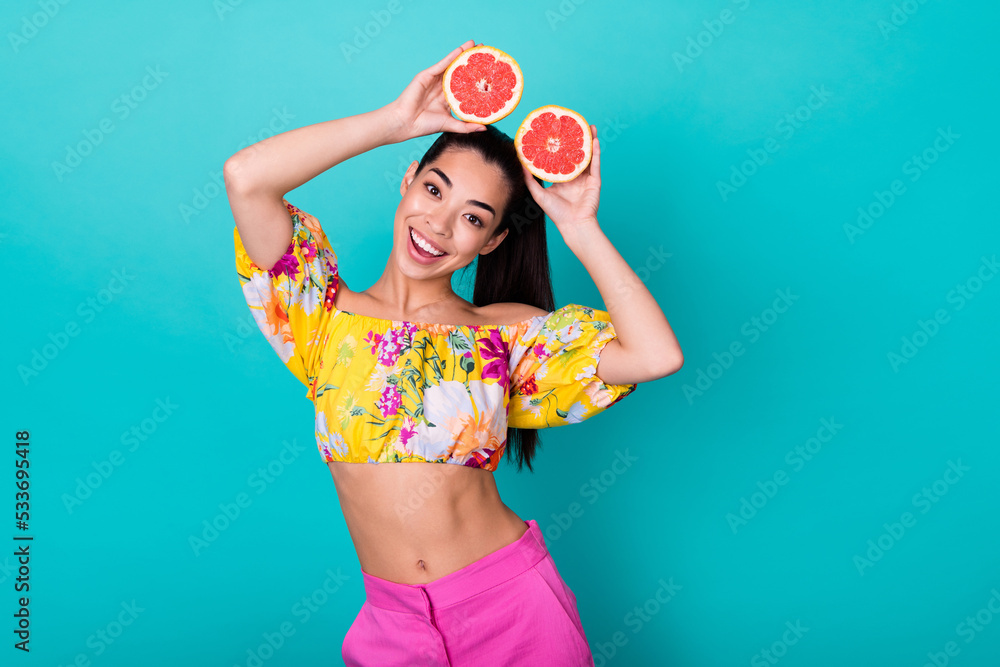 Portrait of young korean funny girl holding fresh grapfruit halves ears grimace isolated on aquamarine color background