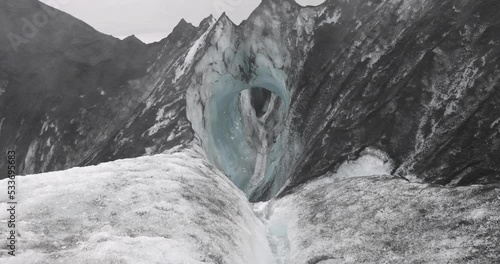 stream water melt from ice flowing through cave in Solheimajokull glacier covered by dark volcanic ash from the volcano Katla under climate change and global warming