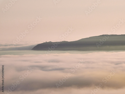Cape Finisterre and its famous lighthouse surrounded by clouds and fog from the Atlantic Ocean.