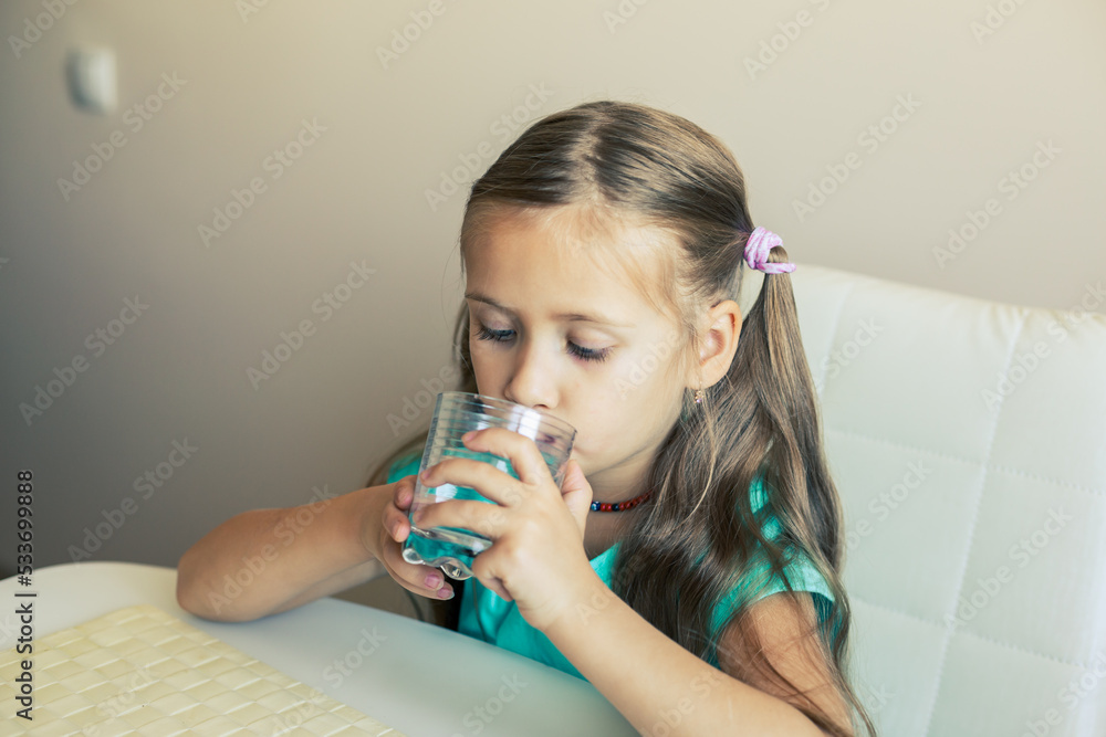 Beautiful little girl drinks clean water from a transparent glass. Beautiful little girl drinks clean water from a transparent glass.