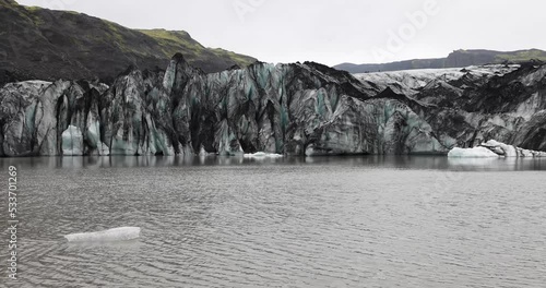 Solheimajokull glacier, Iceland. The tongue of this glacier slides from the volcano Katla. Beautiful glacial lake lagoon with blocks of ice and surrounding mountains. covered by volcanic ash photo