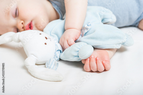 Baby sleeps on bed. Infant sleeps with toy hare