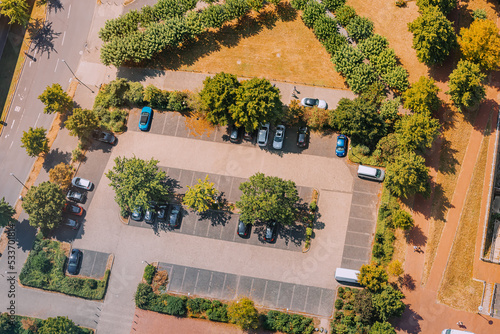 Partking lot with cars in city park among trees. Aerial view