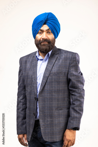 Sikh man with blue turban and grey jacket looking at camera and