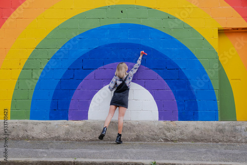 Young woman drawing on rainbow mural