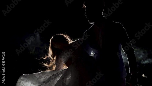 Young couple dance in a dark space with smoke. Slow motion. Silhouette