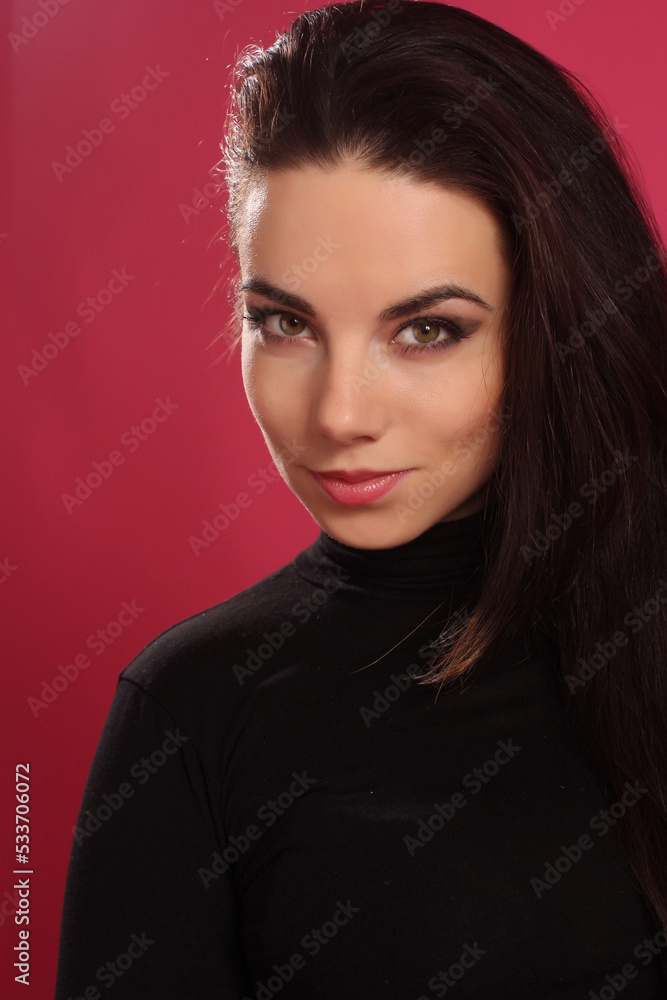 Portrait of a beautiful fashion glamour girl brunette in black clothes in the studio with big earrings on the pink background