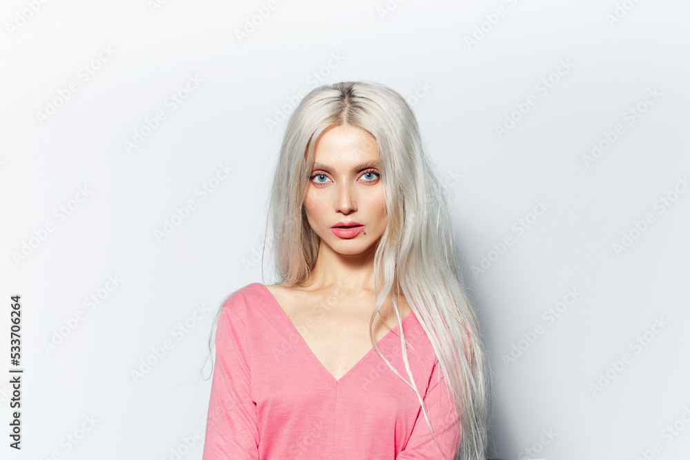 Studio portrait of young blonde pretty girl, wearing pastel pink shirt on white background. Studio portrait of young blonde pretty girl, wearing pastel pink shirt on white background.