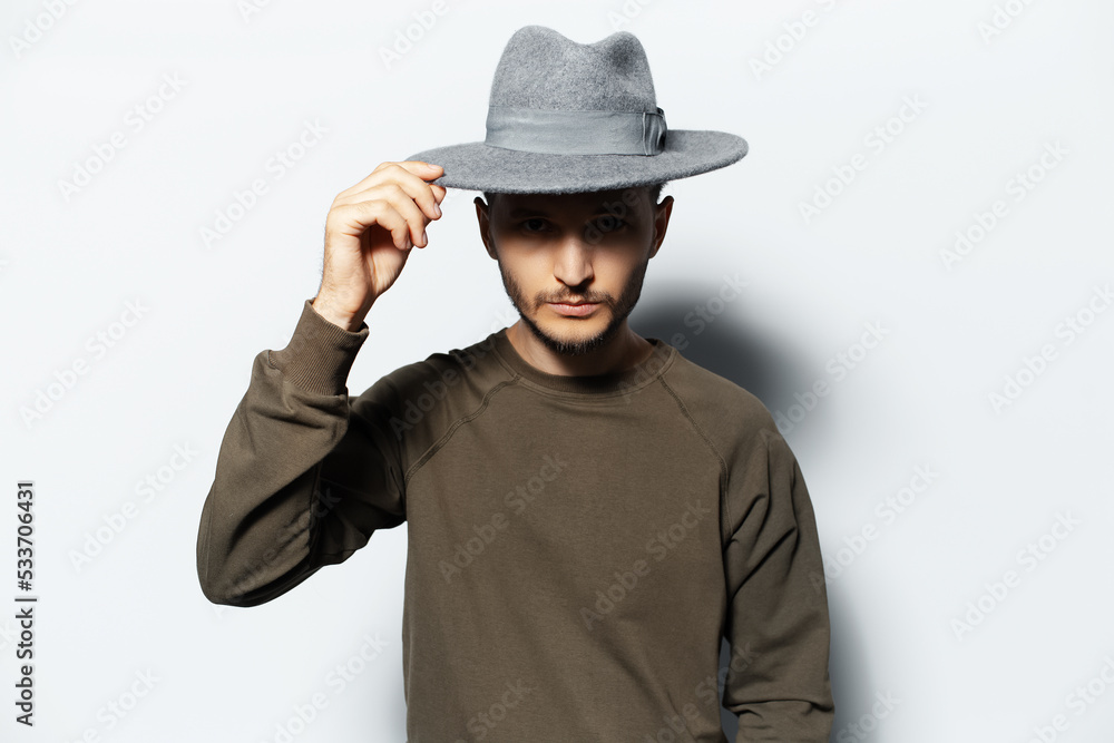 Studio portrait of young man on white background, wearing sweater and grey hat. Studio portrait of young man on white background, wearing sweater and grey hat.