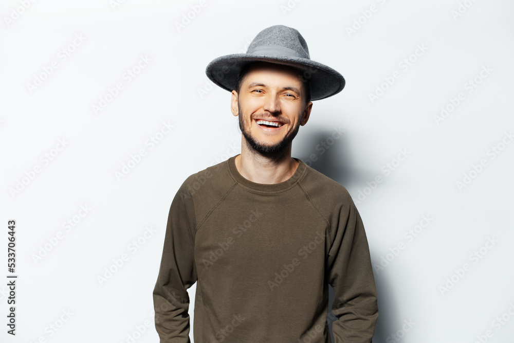 Studio portrait of young laughing man on white background, wearing sweater and grey hat. Studio portrait of young laughing man on white background, wearing sweater and grey hat.