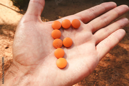 Orange pills are laid out in the shape of the letter F on the palm. Vitamin F.