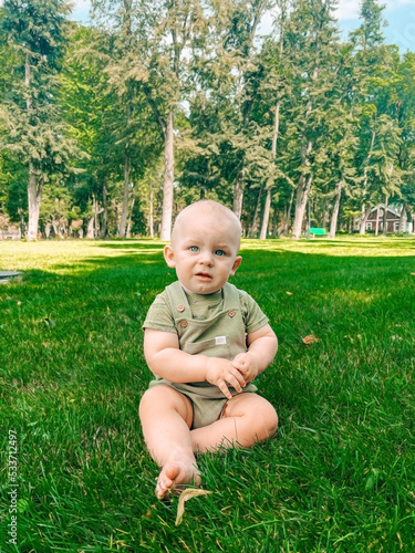 Cute baby boy sitting in the park summer time on the grass