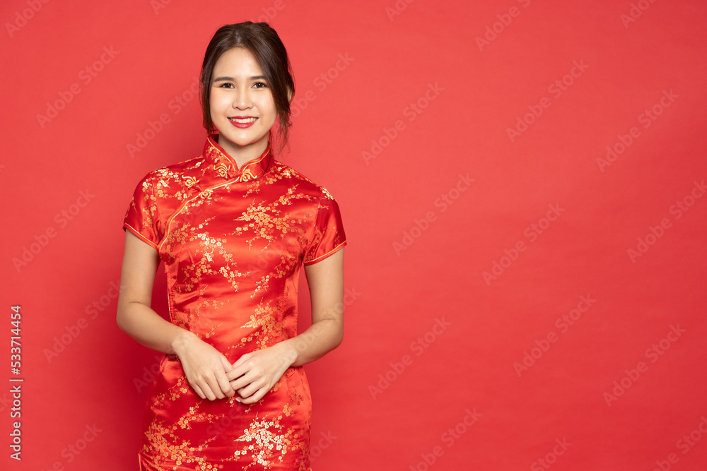 Young Asian woman wearing red traditional cheongsam qipao dress isolated on red background, Happy Chinese New Year concept Young Asian woman wearing red traditional cheongsam qipao dress isolated on red background, Happy Chinese New Year concept