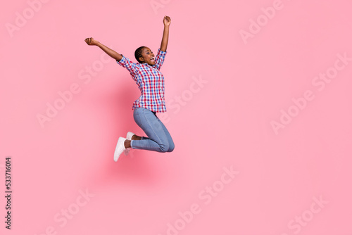 Full size profile photo of overjoyed astonished girl jump raise fists empty space isolated on pink color background
