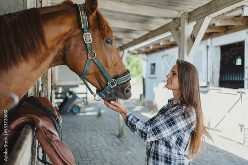 Young woman in a stable with her horse  © pikselstock