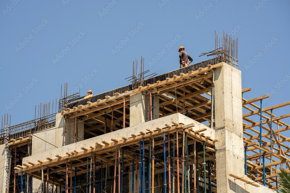 A modern house under construction with builders