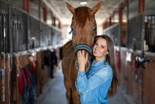 Young woman in a stable with her horse 