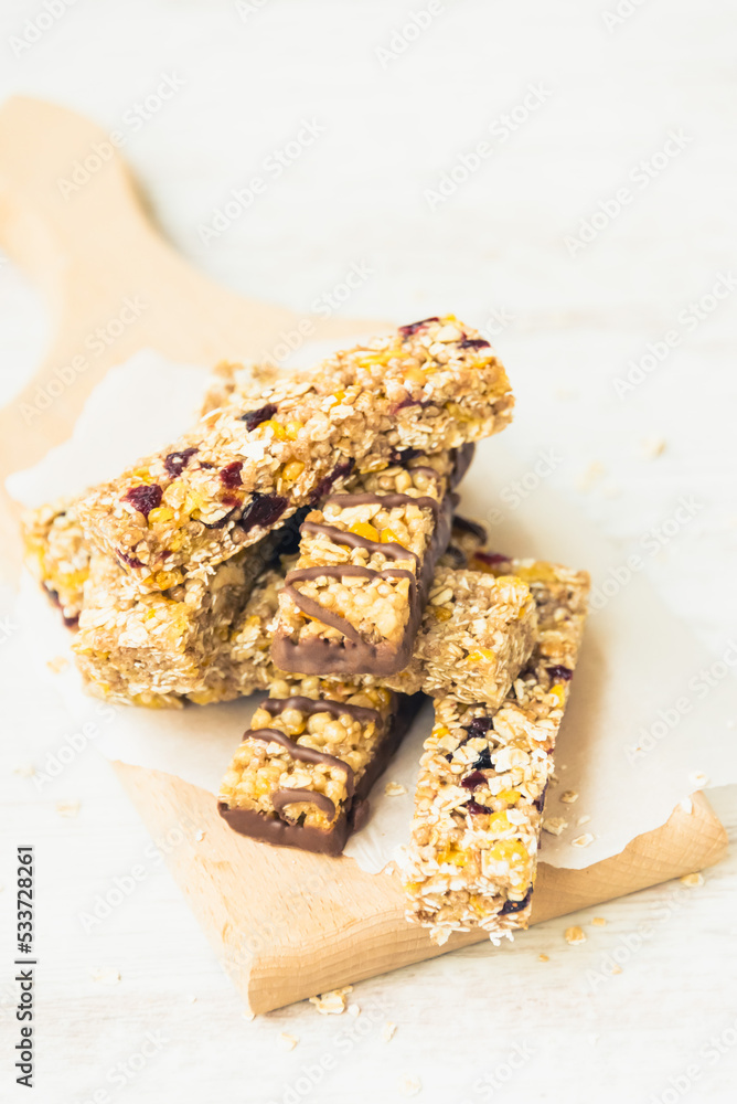 Close view of various homemade granola bars with nuts, seeds, dark chocolate, honey and berries over a wooden board.
